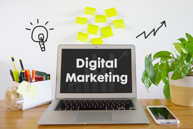 「DigitalMarketing」と表示されたパソコンの横に、スマホやメールなどのアイコンが並んでいる画像
