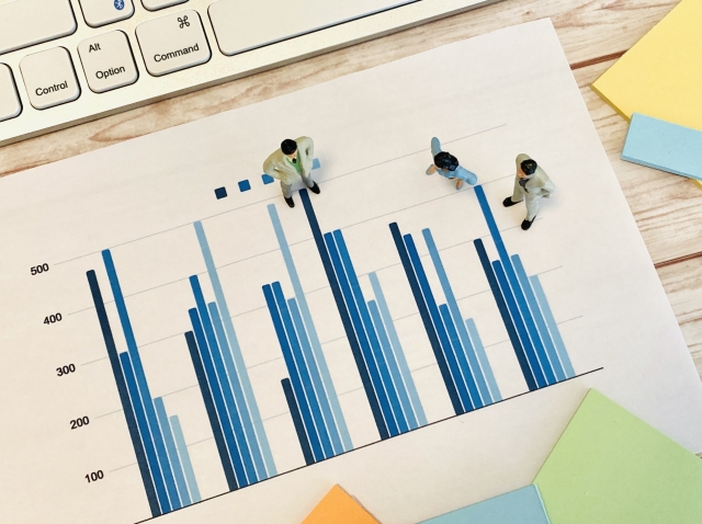 グラフが印刷された紙の上に、人形が3体置かれている様子の画像