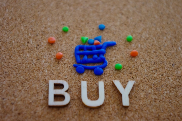 BUYというアルファベットの上に、粘土で出来たカートアイコンが置かれている画像