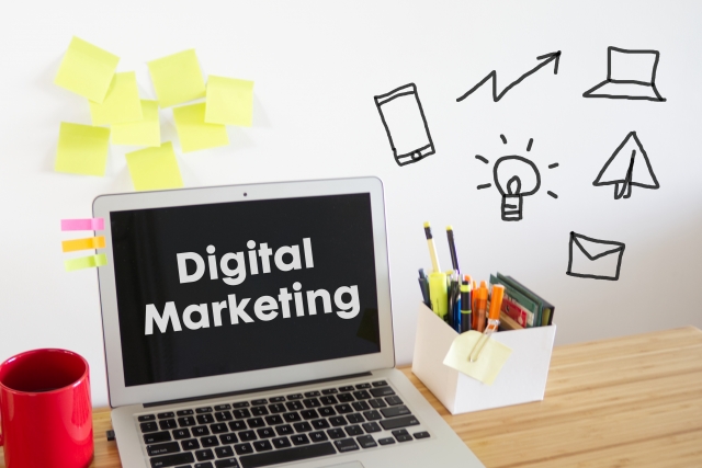 「Digital Marketing」と表示されたパソコンと、筆記用具の画像