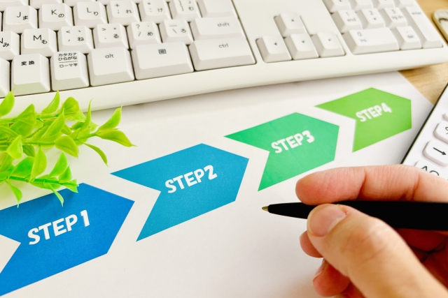 「STEP」と書かれた書類と、ペンを持つ手元の画像