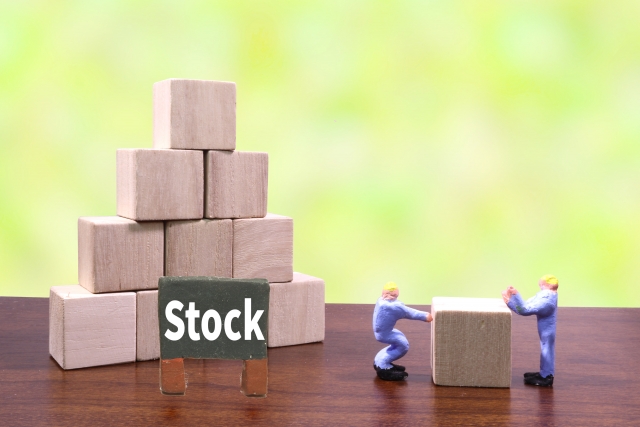 ピラミッド状に積み上げられた積み木の前に「Stock」という表示があり、その横で人形が積み木を運ぼうとしている様子の画像